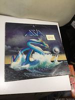 Front cover of Asia vinyl album, featuring fantasy sea serpent artwork and Asia logo, with a sticker showing number 124.