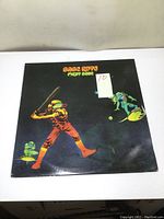 Front cover of Babe Ruth First Base vinyl LP album with illustrated baseball player and other figures.