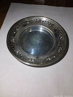 Top down view of round sterling silver dish showing smooth center and openwork border.