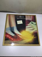 Front cover of Eldorado vinyl LP album by Electric Light Orchestra showing the iconic artwork of a pair of red shoes with socks and a wizard-like hand casting a spell