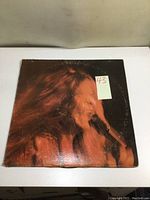 Front cover of Janis Joplin vinyl album featuring a close-up image of the artist singing into a microphone with wear on the jacket.