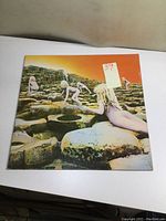 Front cover of vintage Led Zeppelin Houses of the Holy LP showing the iconic orange and yellow sky and nude children on rocky formations.