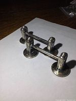 Two sterling silver cutlery rest blocks placed on white sheet showing decorative posts and bars