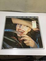 Front cover of The Cars vinyl LP album featuring a close-up image of a woman smiling behind a steering wheel with a price sticker.