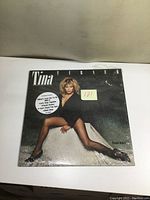 Front cover of Tina Turner LP album "Private Dancer" showing Tina Turner sitting wearing black bodysuit and heels.