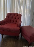 Red Fairfield accent chair with tufted back and rolled arms shown with matching ottoman near window with curtains.
