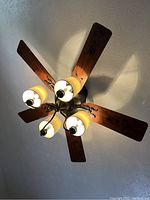 Hunter ceiling fan with five wooden blades and four light fixtures with shades attached, viewed from underneath.