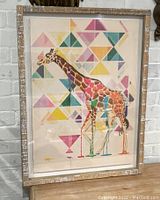 Front view of framed giraffe art print with colorful geometric patterns.
