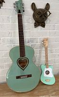 Full view of both guitars with JJ Heart guitar larger and blue with heart soundhole, smaller Loog guitar in mint green and white.