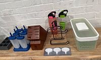 Kitchenware items including storage containers, knife holder, water bottles, popsicle molds, and cheese markers