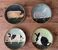 All four decorative plates showing various barnyard animals: sheep, horse, dog, and rabbit, each with checkerboard rim.