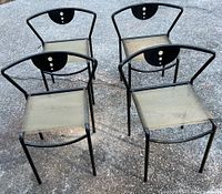 Four chairs grouped on pavement, view from front showing seats and backrests