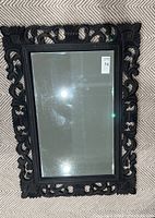 Front view of the rectangular mirror showing carved dark wood frame and reflective glass surface with visible smudges.