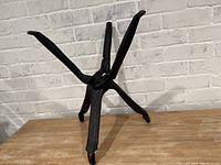 Full view of the dark stained wooden plant stand holder with four legs, positioned against a white brick wall on a wood surface.