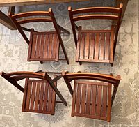 Top view of four wooden folding chairs showing slatted seats and backs on a patterned rug.
