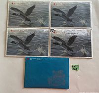 Five blue and gray envelopes from Royal Canadian Mint with wildlife artwork, four with loon design and one solid blue envelope, showing original packaging.