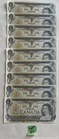 Front view of nine sequential 1973 Canadian one-dollar bills showing serial numbers and front design with Queen Elizabeth II portrait.