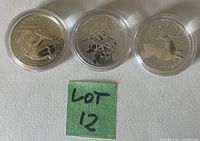 Three coins in clear capsules, reverse sides up showing designs