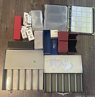 Photo of the lot including coin boxes, cardboard coin holders, plastic sleeves for bills, binders with protective sheets, and coin capsules.