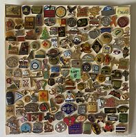 Top-down photo of a flat display board covered with approximately 90 assorted international pins of various colors and designs.