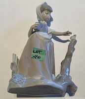 Full view of the Nao Lladro figurine showing the girl reaching out to a bird on a tree branch, with her holding a book in her other hand.