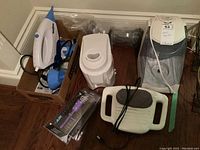 Overview of all items in lot including vaporizers, steamer, massager, and Moulinex appliance with cords visible