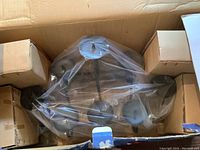 Romantica fireplace candle holder packed inside a cardboard box showing overall black metal structure and condition.