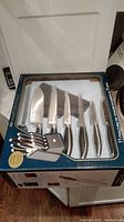 Full set in original box showing 11 knives with varying blade sizes and shapes in plastic pack, front view.