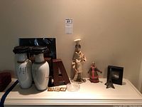 Wide view showing porcelain vases, letter bookends, chef and straw dolls, metal Eiffel Tower, clock and small painted figure.