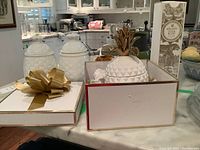 Overall view of ceramic pineapples and packaging, one with gold top and other white ceramic containers on kitchen counter