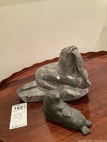 Photo of two indigenous seal carvings on a wooden surface, showing overall shapes and condition.