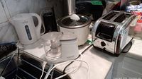 Kitchen countertop with the lot's five kitchen appliances: Salton crepe maker, Black & Decker mini food processor, Rival kettle, Braun coffee grinder, Black & Decker rice cooker