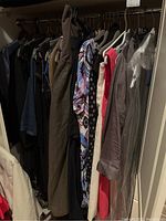 Rack view showing assorted dresses and pants hung on hangers in closet