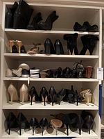 Five shelves of women's shoes and boots, mainly black with some beige and light colors, various styles including ankle boots, heels, and sandals in size 10.