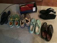 Photo showing all six pairs of men's shoes including a boxed pair of red suede Brooks Brothers, black Timberland boots, green deck shoes with yellow laces, mint green casual shoes, black boots, and brown dress shoes.