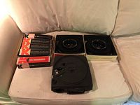 Photo showing Kodak Carousel 600H slide projector front and two Kodak Carousel 140 slide trays in boxes along with five Keystone Universal S-40 slide trays on a white surface.