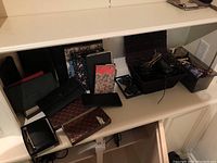 Wide view of collection on shelf showing wallets, address books, notebooks, sunglasses, and baskets