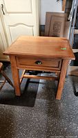Full view of pine side table showing drawer and stretcher base