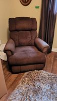Front angle view of a brown fabric reclining chair showing the seat, armrests, and backrest with padded texture.