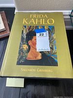 Hardcover art book titled 'Frida Kahlo' by Salomon Grimberg with a greenish-yellow cover and portrait of Frida Kahlo.