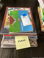 Stack of humor books marked 'HUMOR' sticky note with 'The Far Side Gallery 5' and other books visible.