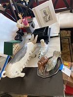 Overview photo showing large pig figurine, white and grey bird figurine, black trays, and art print in frame