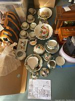 Overview of full set of pottery dinner and serving ware including plates, bowls, teacups, saucers, creamer, sugar bowl, teapot, and serving bowls arranged on the floor.