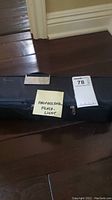 Carrying case placed on floor with note 'Professional Flashlight' and auction tag '78'.