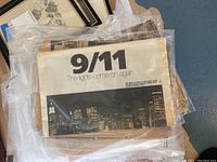 Newspaper with 9/11 headline and city skyline at night, headline states 'The lights come on again.'
