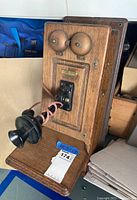 Overall view of the vintage wooden wall-mounted telephone showing the front panel with two metal bells and black handset.