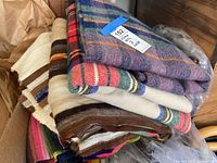 Stack of colorful woven blankets showing plaid and striped patterns with alpaca wool texture