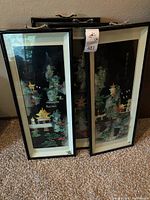 Four framed vertical art panels with Asian inspired imagery and black frames, displayed leaning against a wall, showing their size, colors and framework.