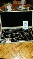 Jewelry box open showing assortment of chains and bracelets on black velvet interior surface, with clip earrings in original packaging.