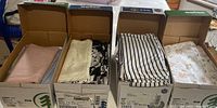 Four open cardboard boxes showing various folded fabrics in different colors and patterns